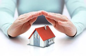hands covering house – insurance concept – real estate