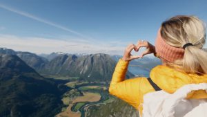 Woman makes a heart shaped finger frame wile hiking in Norway